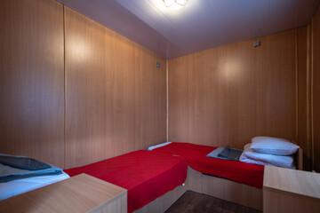 A clean and compact twin room inside a modular cabin, likely used for temporary worker housing. The...