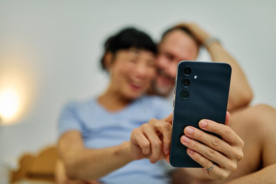 Portrait of a lovely young couple  or friends having fun together using a mobile phone in bed at home