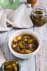 Spicy mexican soup with meat and jalopenos in a bowl on the table vertical view