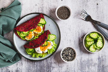 Beet chia tacos with egg, cucumber and lettuce on a plate on the table top view