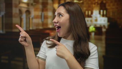 Young hispanic woman smiling and pointing finger at ornate altar in historic church building;...