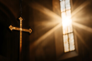 Naklejka premium Warm light streams through a vintage stained-glass window, illuminating a gold cross. Faith, spirituality, belief, hope, religion, and divine light are represented.