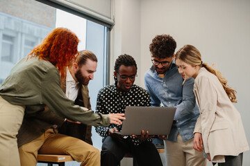 Diverse business team collaborating on project using laptop