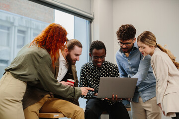 Diverse business team collaborating and discussing ideas on laptop