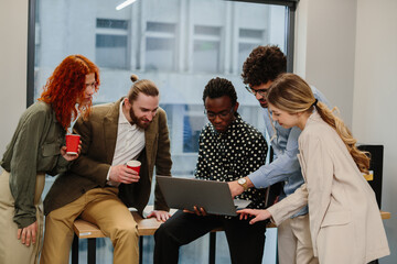 Diverse business team collaborating during meeting, using laptop