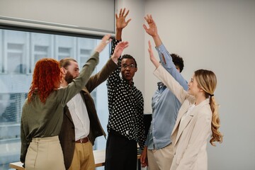 Diverse business team raising hands celebrating success