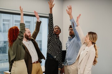 Diverse business team raising hands in office meeting