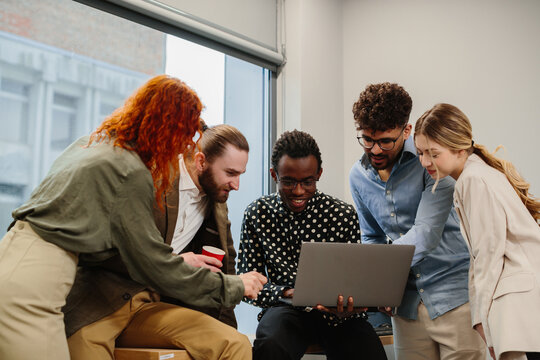 Diverse business team collaborating and discussing ideas on laptop