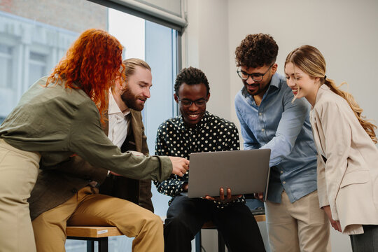 Diverse business team collaborating, analyzing data on laptop