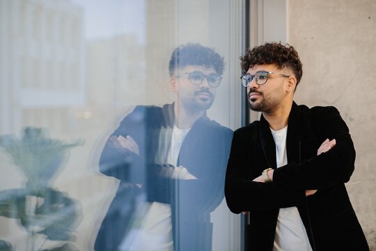 Thoughtful young businessman reflecting by office window