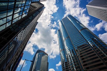 Obraz premium Skyscrapers in Hong Kong viewed from below, with dramatic clouds and sunlight between the towers.