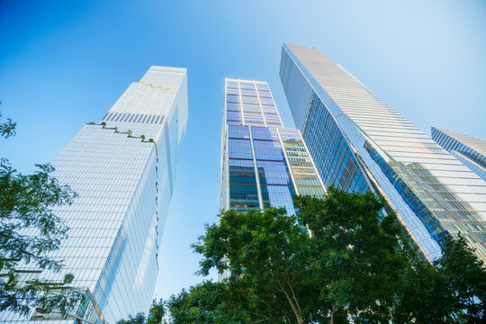 Worm's-eye view of tall modern skyscrapers against a clear blue sky, height strength, architectural lines, luxury building, Midtown Manhattan, New York City, urban cityscape steel, backdrop design art