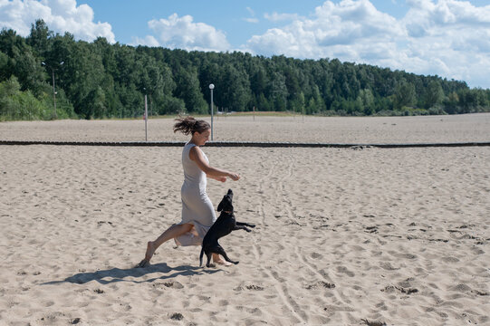 Caucasian woman walking on the beach with her dog. 