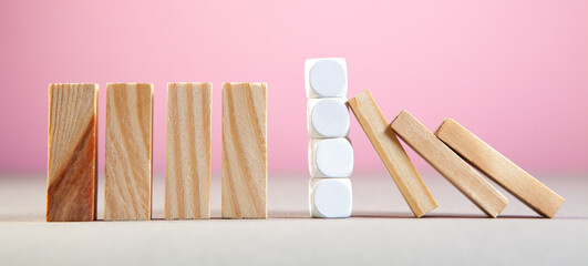 Domino effect with wooden blocks on a pink background. Business concept