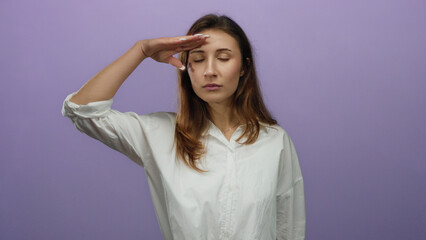 Obraz premium Young woman giving military salute against isolated purple wall wearing white shirt with a serious expression, showcasing determination and strength.