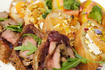 Gourmet appetizers featuring sliced meat on toasted bread, garnished with fresh herbs and colorful toppings, showcasing culinary artistry and vibrant presentation