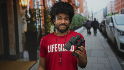 Lifeguard man with binoculars stands smiling on a busy city street showcasing a vibrant scene of urban life and personal expression.
