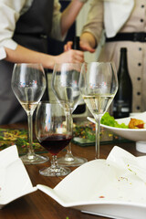 Dirty dishes and empty wine glasses cluttered on a wooden table after a festive gathering, showcasing remnants of a joyful dining experience with vibrant colors and textures
