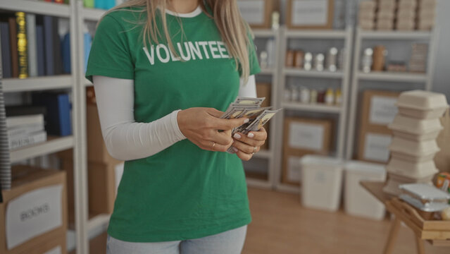 Woman volunteer counting money in a charity center filled with donation boxes and packed meals, showcasing the organized indoor environment of a dedicated donation room.