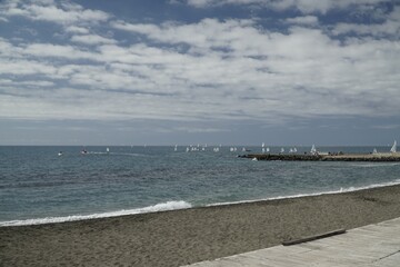 A series of sailing boats from a sailing school on the horizon.