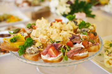Colorful platter of assorted appetizers featuring various toppings, garnished with fresh herbs, displayed elegantly on a glass serving dish for a festive gathering or event