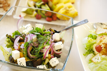 Fresh salad featuring vibrant greens, colorful vegetables, and feta cheese, served in a clear glass bowl, showcasing healthy eating and culinary presentation
