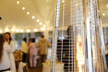 Heat gun providing warmth in a tent during a cold weather event, creating a cozy atmosphere for guests enjoying the gathering and enhancing comfort levels