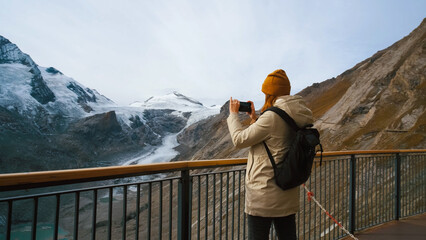 Person capturing stunning glacier landscape at mountain viewpoint during daytime