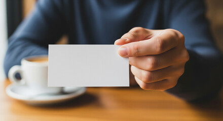 Businessman holding a blank white business card towards the camera, a perfect mockup for displaying a brand, name, or professional contact information