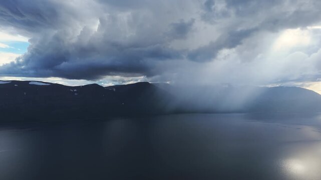 Aerial view of rain curtain and bright ray over calm surface of Lake Lama near remote Putorana. Misty streak and luminous patch glide across water, perfect for tourism promo and nature storytelling