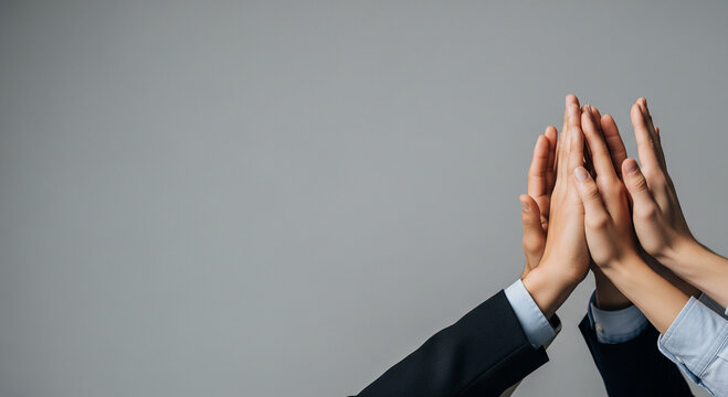 Close-up of two business professionals giving a high-five against a neutral background, a perfect concept for partnership, agreement, and celebrating success