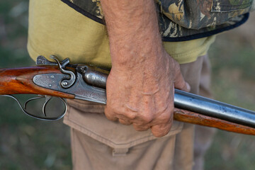 Close-up of a hunter's hand with a gun. Medium shot of a hunter with a weapon.