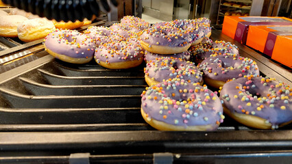 Donuts with purple icing - A tray of delicious donuts covered in sweet purple frosting and colorful rainbow sprinkles