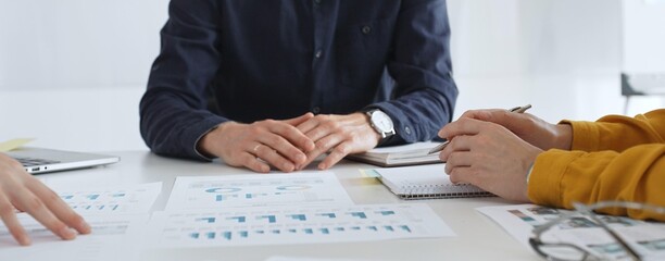 Business people team analyzing financial data and discussing growth strategy during meeting, pointing at charts and graphs, taking notes in modern office