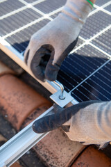 Installation of solar panels on a rooftop during clear weather with a worker securing them in place