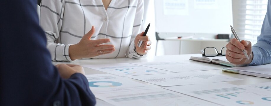 Business team meeting with financial documents and charts, discussing data analysis, planning strategies, and corporate success during collaborative teamwork session