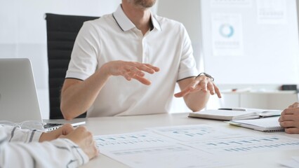 Business team reviewing financial charts, collaborating intently around conference table in contemporary workspace, sharing insights during strategic planning session in office meeting room