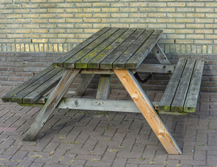 wooden picnic bench stands outside against a brick wall