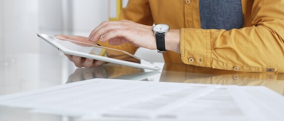 Person using a digital tablet for business at desk, navigating online content or browsing documents. Audit and taxes in business