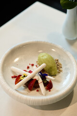 Gourmet dessert with meringue, strawberries, and green sorbet