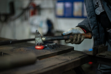 In the blacksmith's workshop, the blacksmith is leveling the red-hot metal with a hammer. A red-hot...