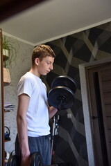 Teen boy exercising with dumbbells at home, lifting weights in casual sportswear — healthy lifestyle, strength training, and fitness motivation concept.