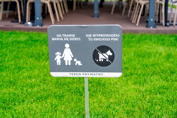 Close-up of a no dogs allowed sign in a public park in Poland with greenery in background
