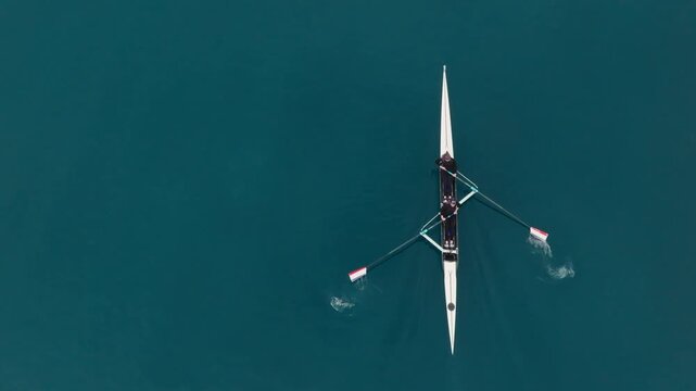 Two athletes rowing a sculling boat on calm blue water, teamwork and endurance in competitive sport. Rowers are practicing sport rowing. Rowers in a racing boat row in slow motion video 120fps.