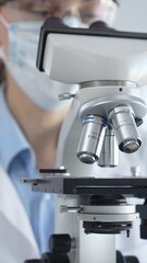 Scientist wearing lab coat and protective glasses using a modern microscope in a laboratory setting, conducting research and experiments in a scientific environment. Health care and science concept