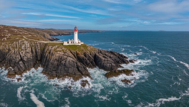 Lighthouse Standing Tall on Rocky Coastline Overlooking the Ocean Under a Bright Blue Sky