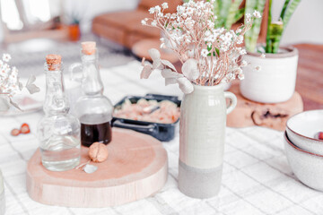 Elegant arrangement of decorative vases with dried flowers on a wooden cutting board, surrounded by glass bottles and bowls, creating a cozy and inviting atmosphere in a modern interior