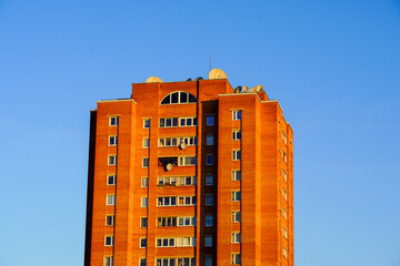 Brick apartment building under clear blue sky during golden hour in urban setting