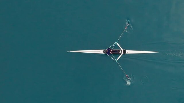 Rowing Top view of professional rower in racing boat, symbol of strength, determination and healthy active lifestyle. Single scull athlete training on water, in slow motion video 120fps.