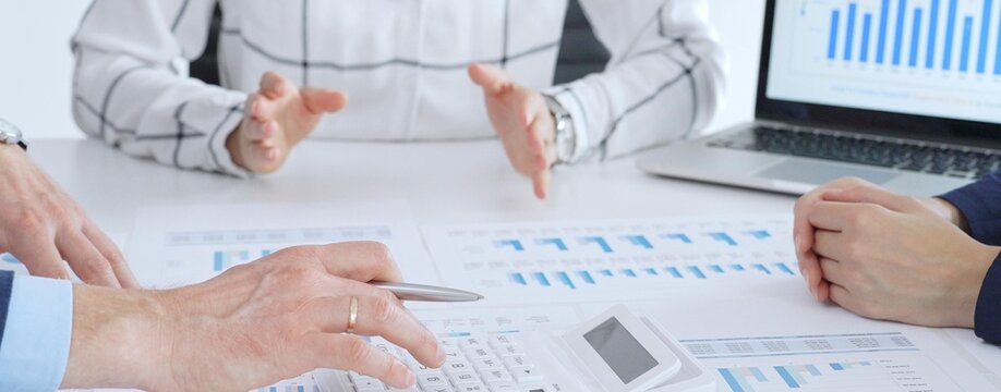 Business people or accouters analyzing financial data using charts, graphs, and reports during an office meeting, collaborating on strategy